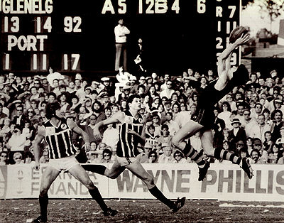 Stephen Kernahan marks during the third term of the round 19 match at glenelg Oval against Port Adelaide, 1982. Port Adelaide's Steve Curtis and Ben Harris can only watch. The scoreboard tells the story of the match. * Photo courtesy of Gerry McGinley.
